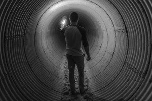 Ein Mann leuchtet in einen dunklen Tunnel mit einer kleinen Lampe.